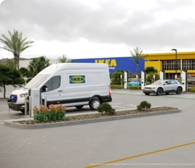 An IKEA parking lot with an IKEA van charging at an Electrify America charging station with more charging stations in the background with an electric vehicle charging.